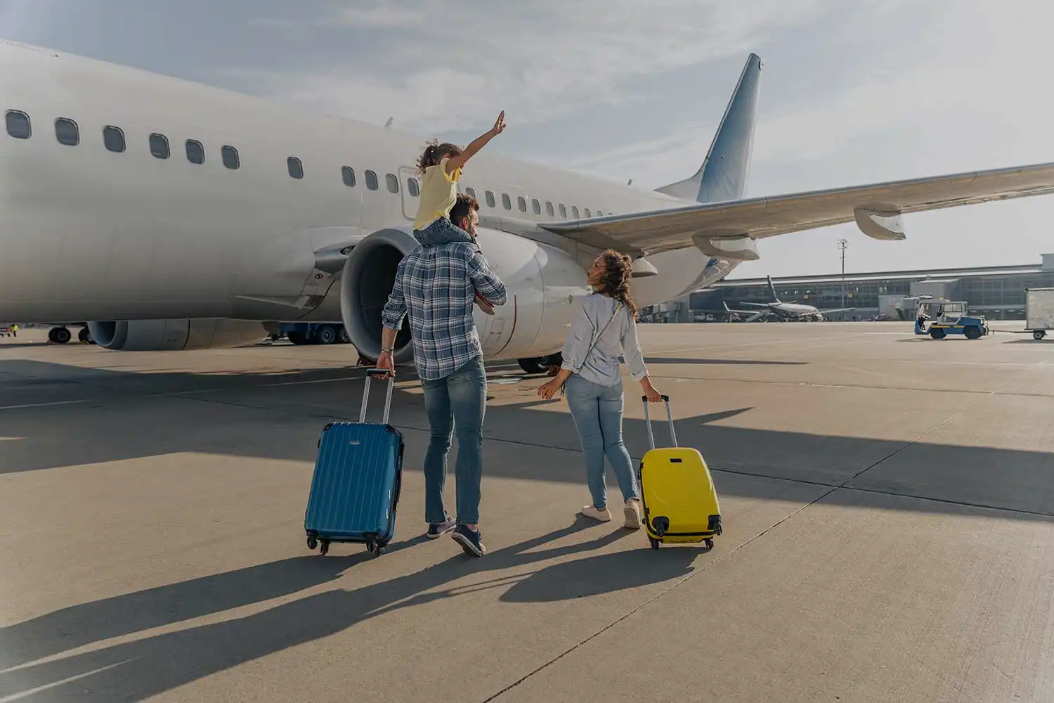 Famille heureuse marchant vers un avion avec bagages