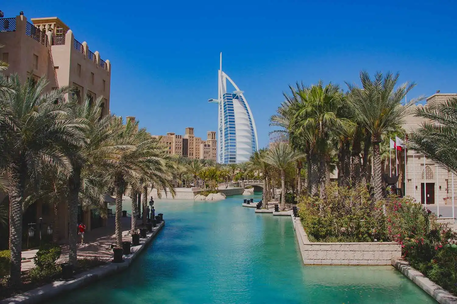 Vue sur l'hôtel Burj Al Arab à Dubaï, entouré de palmiers et d'un canal d'eau turquoise