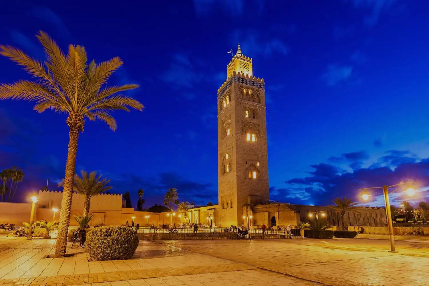 Tour de la Koutoubia à Marrakech au crépuscule, avec un ciel nocturne bleu et des palmiers