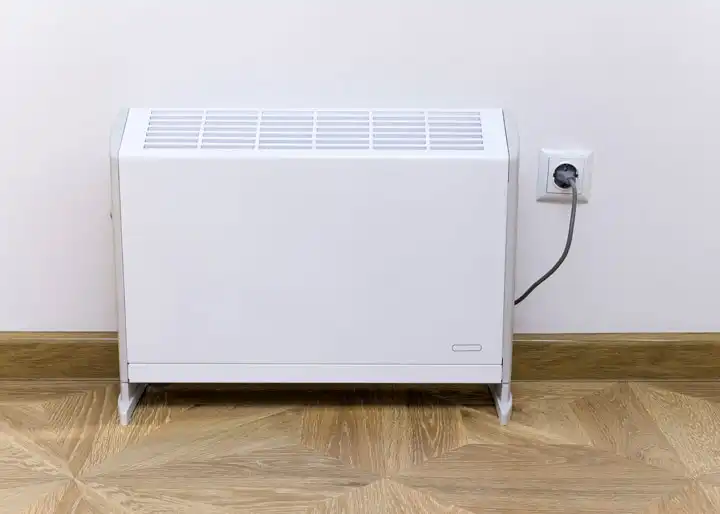 Radiateur électrique blanc fixé au mur branché à une prise électrique