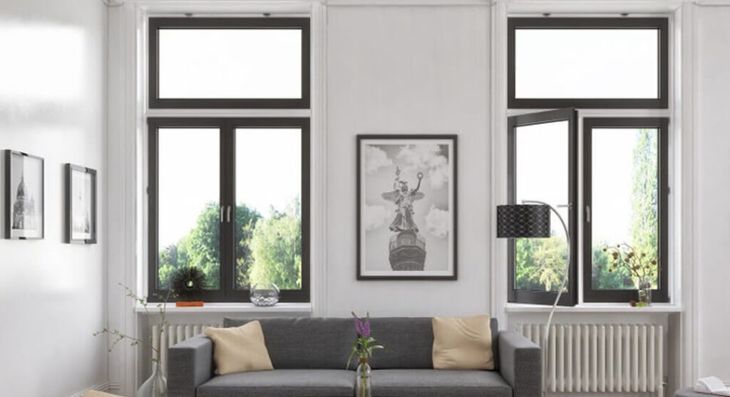 Salon élégant avec hautes fenêtres noires et décoration murale.