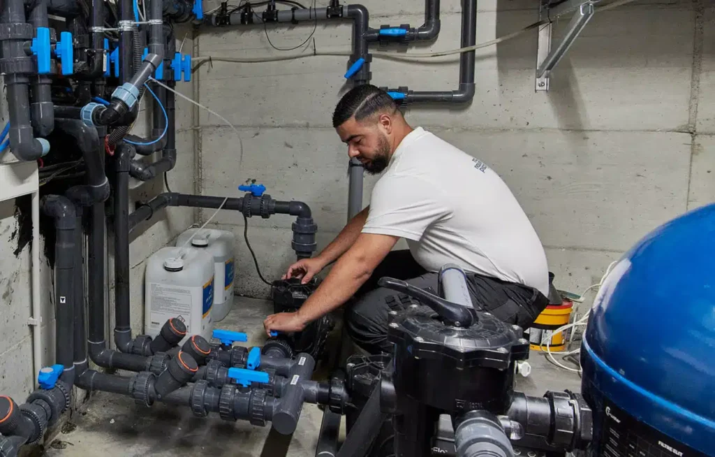 Technicien ajustant le système de filtration d'une piscine.